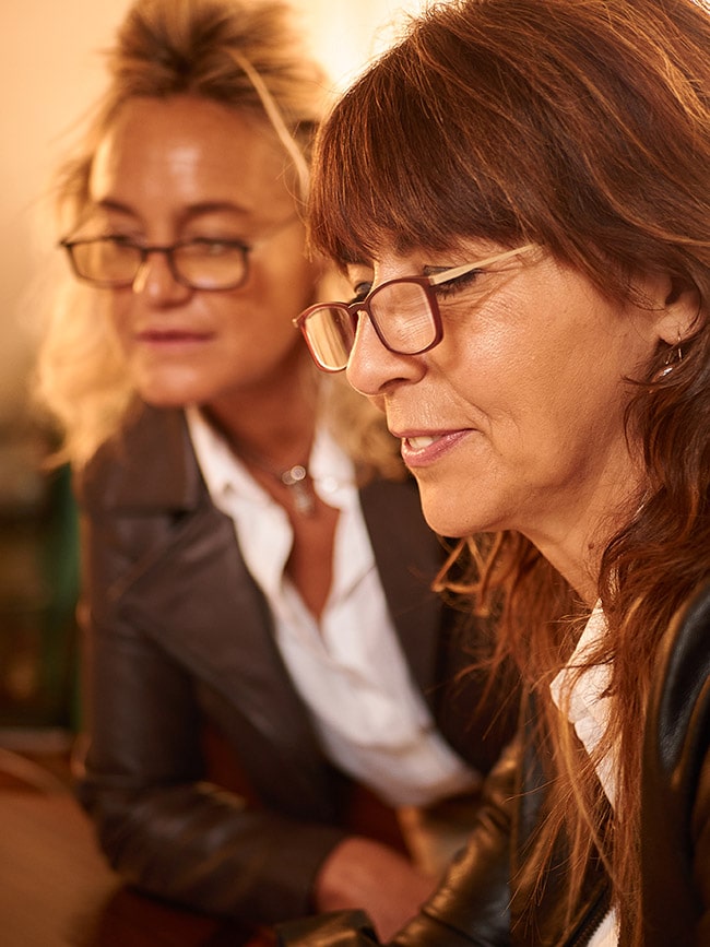 Dos mujeres de mediana edad mirando una pantalla con gafas de lectura Contour modelo Zaska